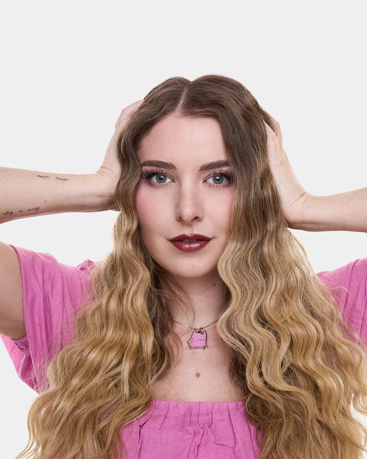 Porträt von Paula Wolf mit langen gewellten Haaren und pinkem Oberteil